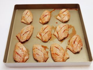 香辣烤翅,腌好的鸡翅放入烤盘中，在鸡翅上刷上几层腌料