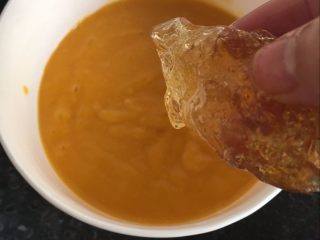 芒果布丁【爽滑美味又解暑】,将吉利丁片放入微热的芒果汁中，搅拌到融化。