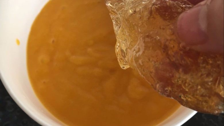 芒果布丁【爽滑美味又解暑】,将吉利丁片放入微热的芒果汁中，搅拌到融化。