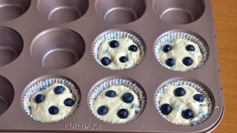 蓝莓爆浆麦芬蛋糕,将面糊舀入纸托中，上面各放四颗蓝莓。