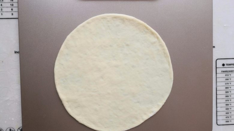 培根薯角薄底披萨,把醒发好的面团擀成薄薄的面饼，放到烤盘上。