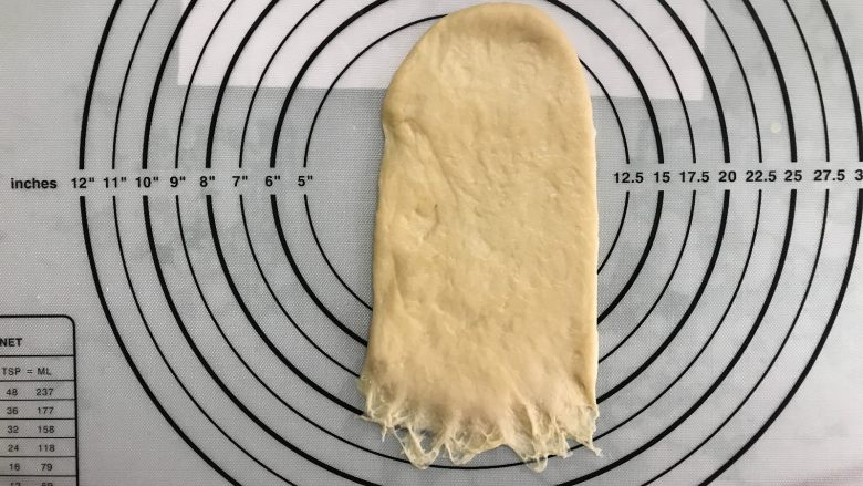 芝麻软面包,取一面团，按扁后擀成长舌形，拍去边上空气。翻面，底部压薄。