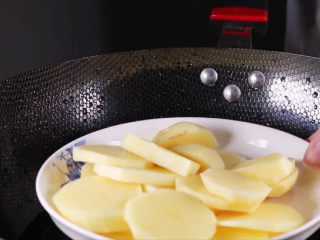 土豆饼的家常做法，吃起来特别过瘾,将土豆片装盘下锅隔水蒸。