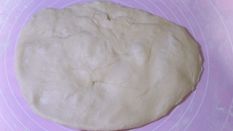 汤种紫薯花卷面包,发酵好的面团，拿出来按压排气，然后揉圆盖上保鲜膜进行醒面15分钟