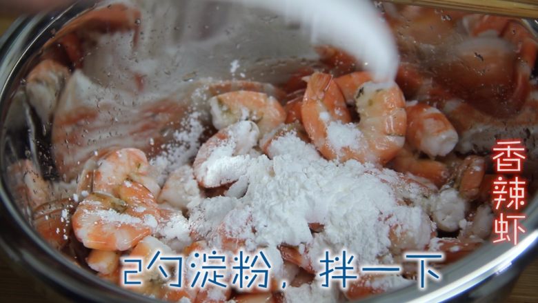 香辣虾,挤干水分、放入盆中、加入一勺盐腌味、放入两勺淀粉、拌均匀。