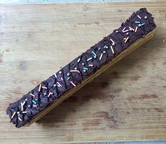 西番尼蛋糕,将巧克力酱趁热抹在蛋糕片上面，再挤上巧克力线条，最后撒上彩色糖粒装饰