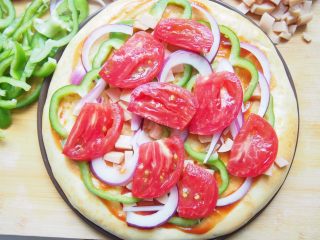 番茄鸡肉肠披萨,铺上适量的洋葱丝和青椒丝，最后铺上一层番茄片。