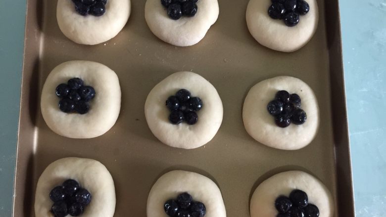 酥粒蓝莓面包,在每个面团的中心放入几颗新鲜蓝莓，再用手往下压压