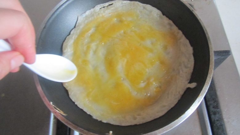 煎饼包油条,翻个面，继续煎至，将鸡蛋刷满饼底；