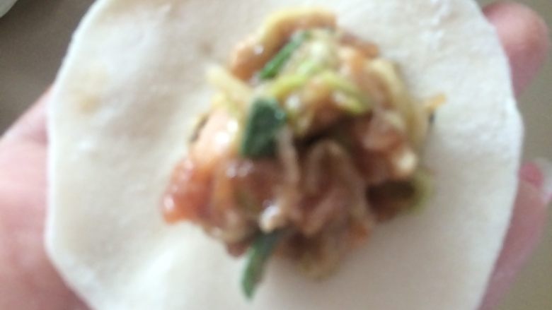 家常水饺~西葫芦猪肉馅,饺子皮中间包入拌好的饺子馅，再将边缘对折捏紧。