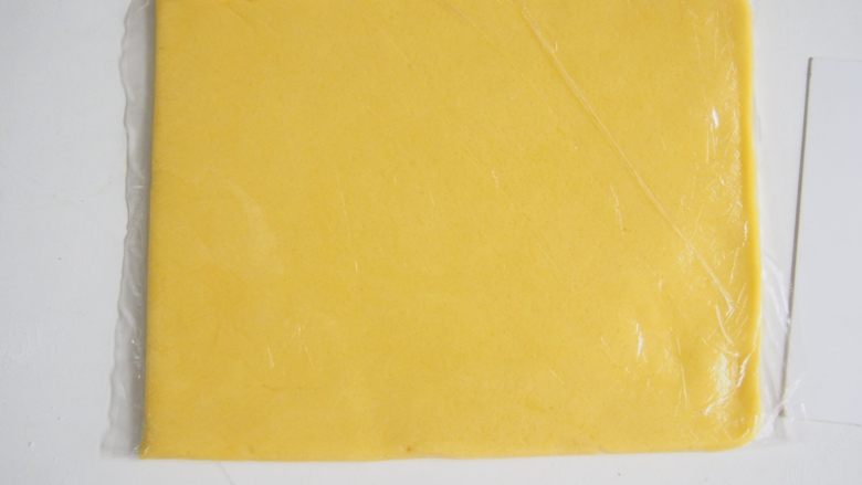 蛋黄奶酥,放入保鲜袋中擀成0.6cm左右厚度的薄片，放入冰箱冷冻1~2小时至硬
