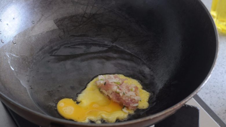 >荸荠瘦肉鸡蛋饺子,等待片刻，看到鸡蛋液底部微微凝固，将肉馅放在鸡蛋液的一边