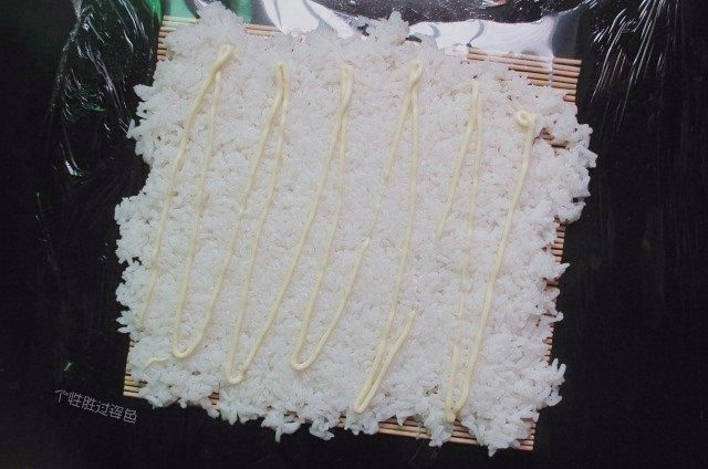 手卷饭团,用饭铲把米饭进行调整铺平，挤上沙拉酱