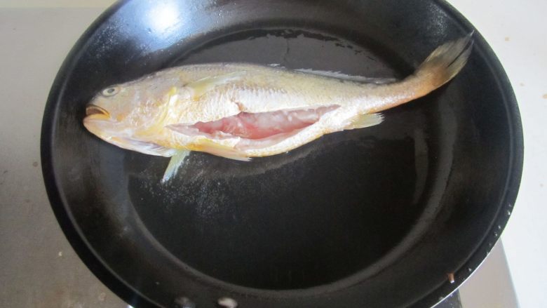 毛豆烧黄鱼,烧热锅，放入少许油， 将黄鱼放入里面进去煎；