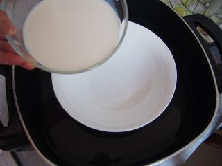 红豆奶油小方,锅中隔水放入一个碗，倒入牛奶。