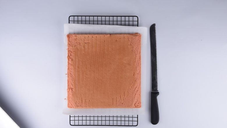 草莓花式蛋糕卷,冷却的蛋糕胚翻过来有草莓画那面朝下，用锯齿刀将相对的两边倾斜45度切去边缘部分