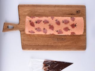 草莓花式蛋糕卷,可可糊装入裱花袋里，在蛋糕卷草莓部分点上小点，画出叶子