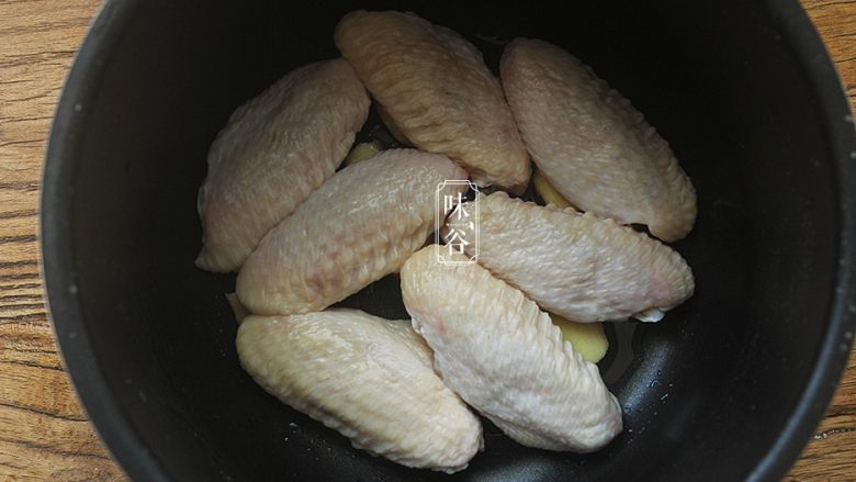 简单方便的电饭煲可乐鸡翅,放进鸡翅，鸡翅皮朝上，姜片要放在鸡翅底下，这样去腥，防止粘锅。