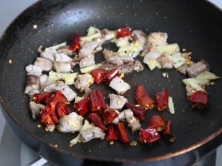传统秘制 梅干菜扣肉,放入五花肉丁、姜、辣椒段翻炒至肉丁出油。