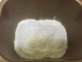 汤种法玉米香肠辫子包,将水放入面包桶中之后加酵母静置2分钟后放入高粉、低粉、汤种、细砂糖、盐、奶粉和蛋液之后启动面包机的揉面功能30分钟