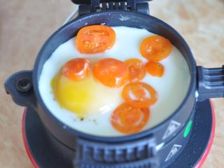 蔬菜总荟汉堡,将早餐机上层的组件放下，先刷一层油，再打入鸡蛋，表面撒一点盐，盖上上面盖子，持续加热让鸡蛋凝固。
鸡蛋凝固后，放下切片的圣女果。