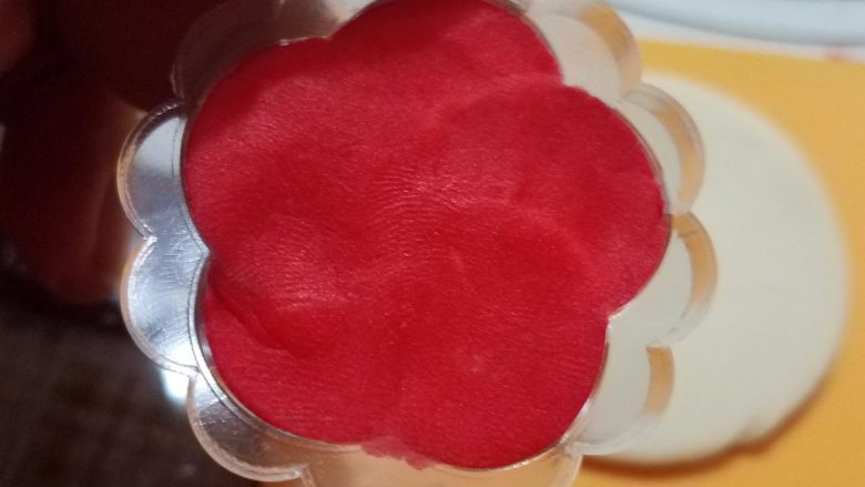 桃山皮月饼,取出2-3g带颜色的桃山皮，按在花片上面，多余的部分用牙签挑出来，刮平没有凸起才可以，否则整体压型的时候，会影响花纹效果