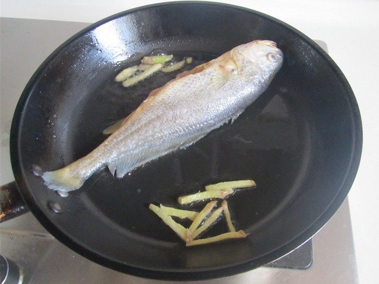 黄鱼焖豆腐,将黄鱼放入锅中煎；