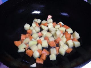 鸡丁炒土豆,锅内加油倒入土豆丁、胡萝卜丁煸炒（油的量要比平时多一点）