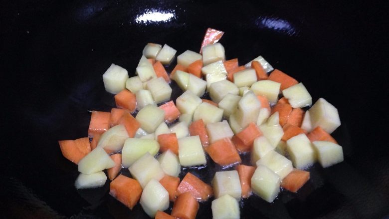 鸡丁炒土豆,锅内加油倒入土豆丁、胡萝卜丁煸炒（油的量要比平时多一点）