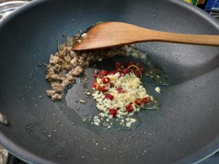 腌酸豆角懒人法,将肉末划到锅一边，放入蒜末，辣椒在油里煸香。
