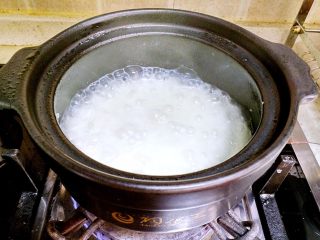 香肠砂锅煲仔饭,听到砂锅煮开后，把砂锅盖打开，用木铲搅拌一下大米。