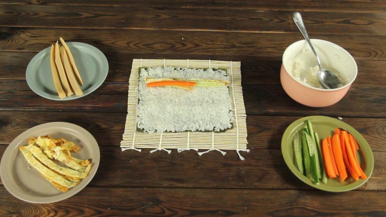 花样寿司の紫菜卷,在米饭上依次铺上鸡蛋条、胡萝卜、黄瓜