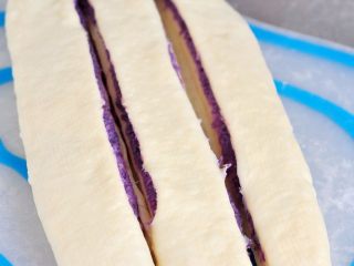 紫薯辫子土司,用锋利的刀把中间切开，切两道，把面皮平均分成三等分，顶部留些空不要切断。