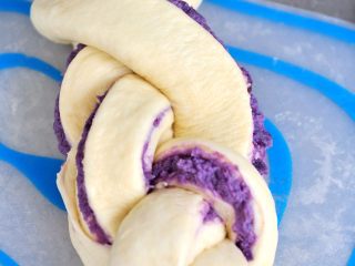 紫薯辫子土司,利用编辫子的方法，把面团折叠编好，把底部捏紧封口，移到土司盒中。
