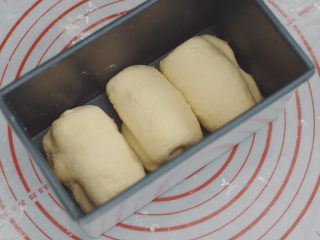 吃不腻的奶香吐司,像这样放在模具里。左边两个卷口向左，右边的一个卷口向右。