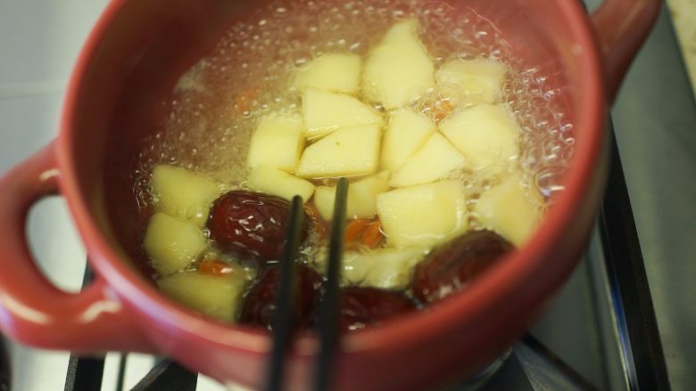 超好吃的苹果炖牛腩,6、	取砂锅一个加入开水、一个苹果去皮切块煮五分钟筷子可以轻轻夹断