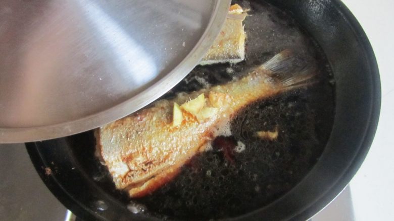 家常烧刁子鱼,将腌制的姜片和白酒一同倒入， 再加入适量的水， 加盖炖煮五分钟；