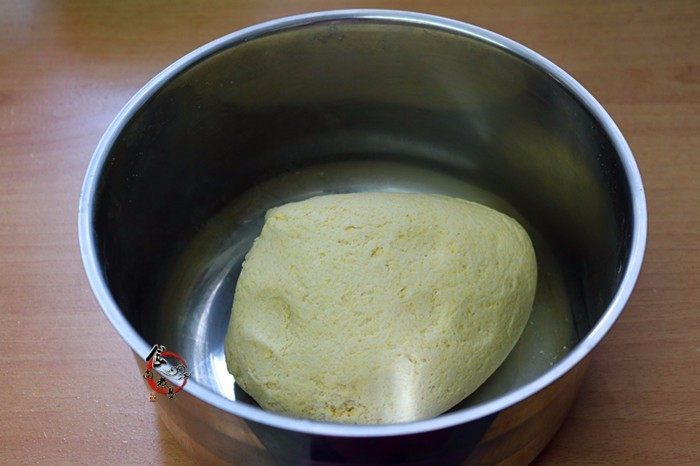 玉米面豆沙板栗包,慢慢加入温水，搅拌成大片雪花状的面絮，能成团时停止加水，揉成光滑柔软的面团，遮上保鲜膜，静置饧发20分钟左右