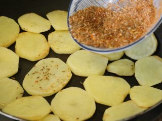 孜然土豆,土豆两面金黄，8分熟后，撒入搅拌好的孜然辣椒面，调料拌匀。