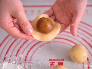 【烘焙配方】经典广式月饼,硅胶垫上撒少量粉，取一个小面团用手压扁，中间放一颗月饼馅