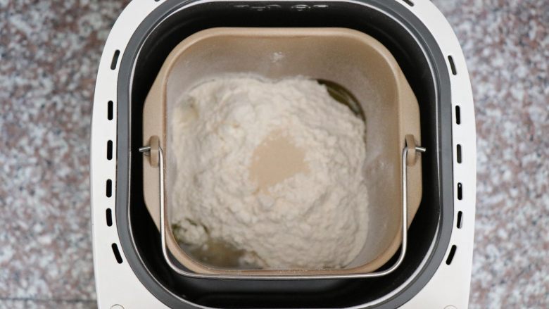 迷迭香佛卡夏,将面团中的所有食材按照先液体后固体的顺序放进面包机桶内，酵母放面粉中间，盐、糖对角放，选择和面功能；