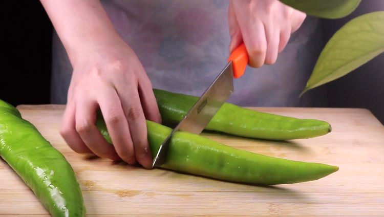 往青椒里塞入半斤金针菇，这味道绝了！,接着我们来处理尖椒，用刀子将尖椒对半切开。