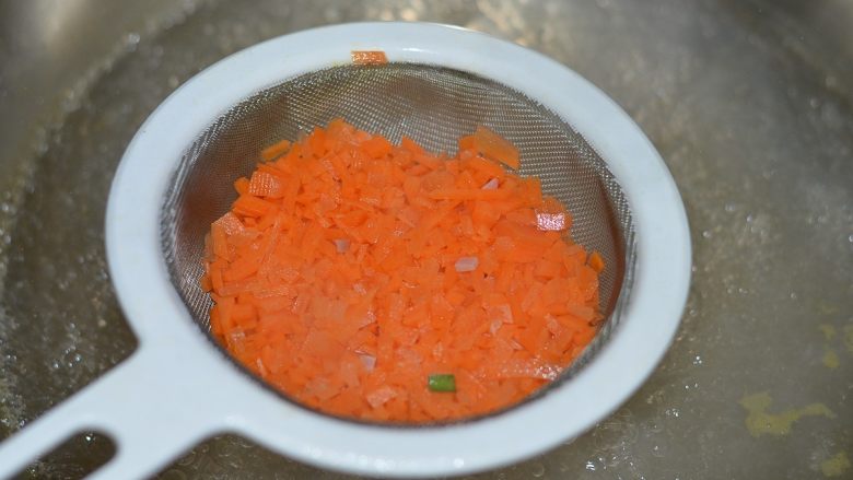 胡萝卜火腿煎蛋，越吃越爱,坐锅烧水，水开后用滤勺把胡萝卜焯水。因为太碎了，这样焯水比较省事儿是。