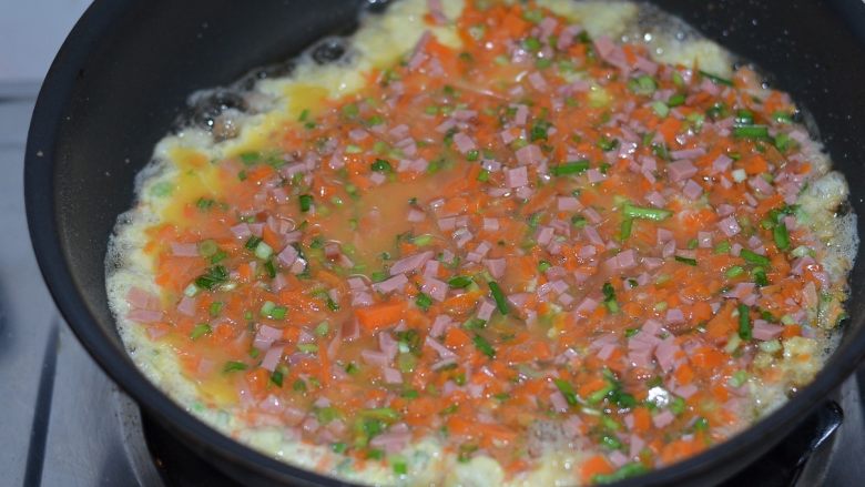 胡萝卜火腿煎蛋，越吃越爱,平底锅倒油烧热，将蛋菜液下锅，中火煎定型。