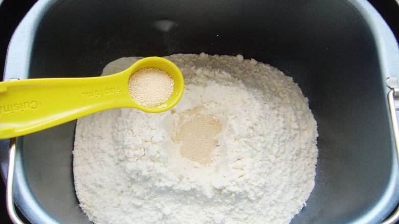 火龙果软欧包,面粉中间挖小坑倒入酵母粉盖上，一角处倒入盐。（避免酵母粉与盐直接接触影响活性）