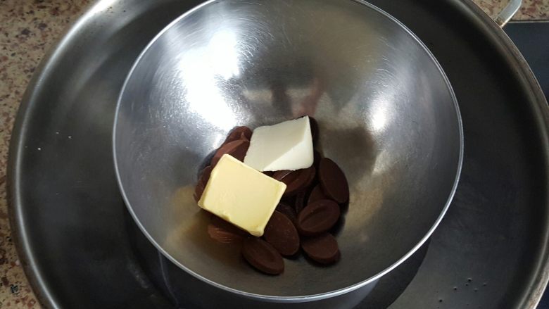 白色恋人,接下来我们做蛋糕体部分，将黄油和黑色巧克力币放入盆内，隔水融化。