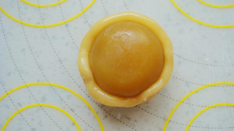广式莲蓉蛋黄月饼,饼皮按扁放入馅料，同样方法用虎口慢慢上推捏紧收口包好。