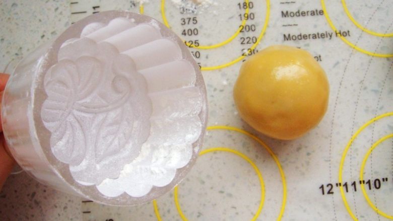广式莲蓉蛋黄月饼,模具里安上喜欢的花片，撒上干面粉，使周围均匀的沾满面粉，再把多余的面粉抖出来。这样在脱模的时候不沾。