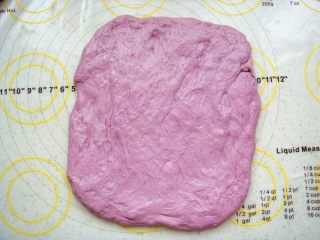 紫薯软欧包,取一份用擀面杖轻轻的擀成接近长方形的面片。