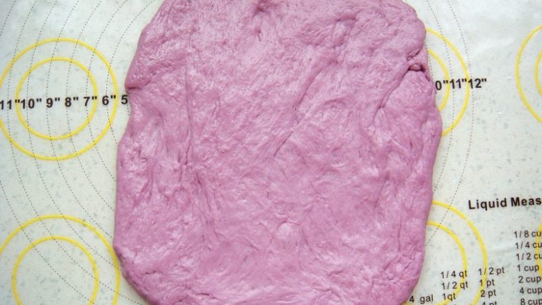 紫薯软欧包,取一份用擀面杖轻轻的擀成接近长方形的面片。